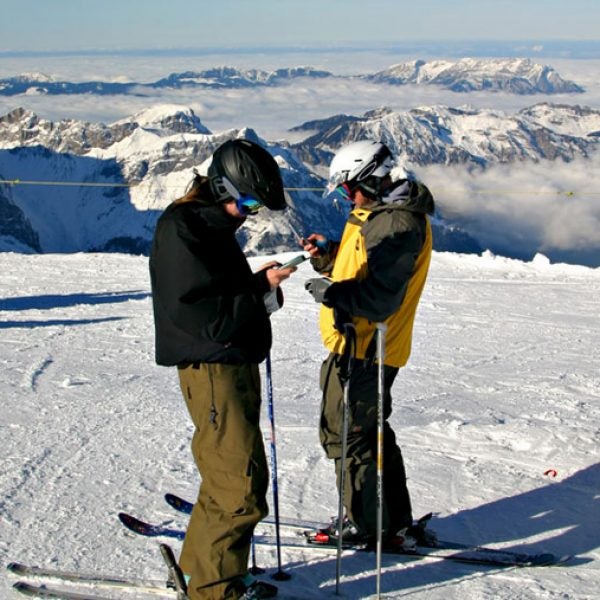 Two skiers calling from their cell phones on top of mount Titlis Switzerland