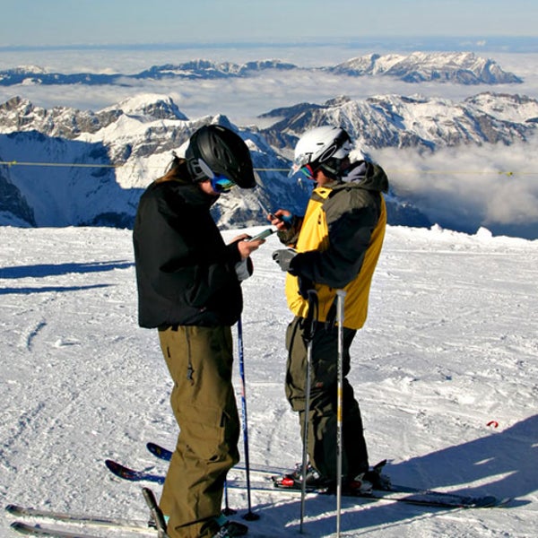 Two skiers calling from their cell phones on top of mount Titlis Switzerland