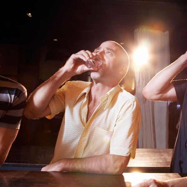 Hispanic men drinking shots at bar.